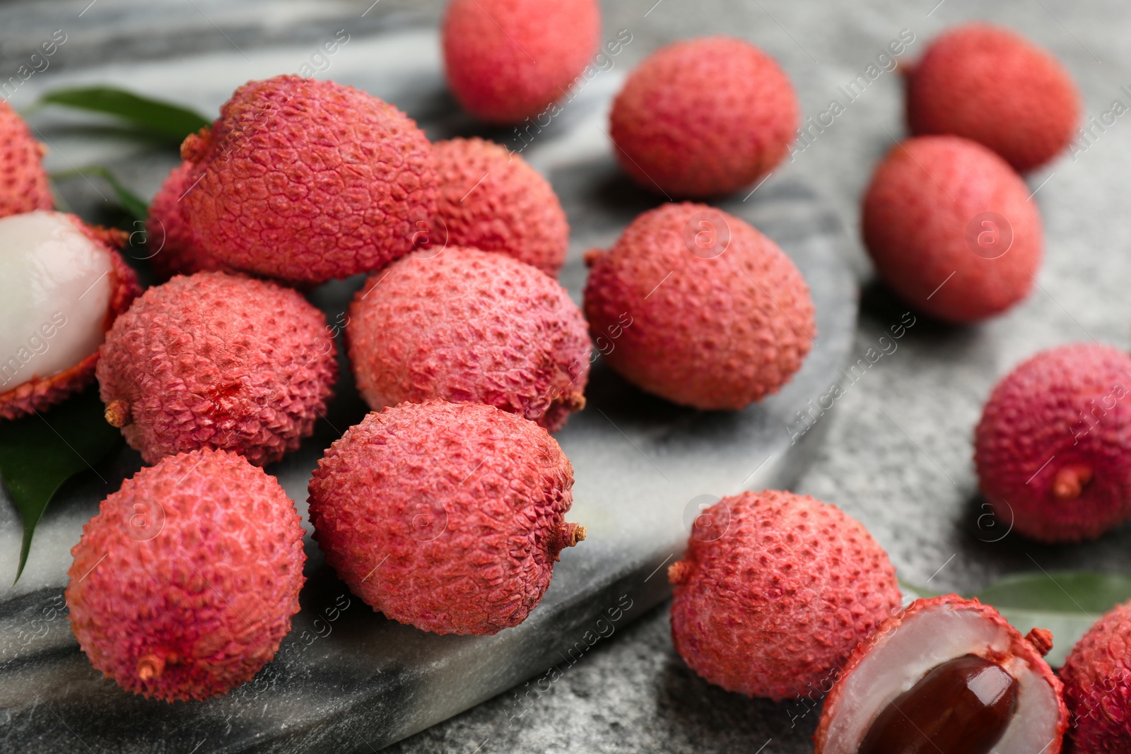 Photo of Fresh ripe lychee fruits on grey table, closeup