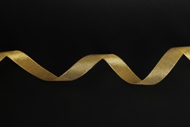 Photo of Elegant gold satin ribbon on black background