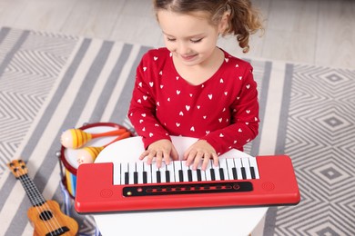 Photo of Little girl playing toy piano at home