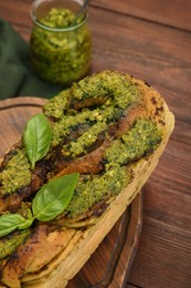 Freshly baked pesto bread with basil on wooden table, above view