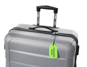 Photo of Grey suitcase with TRAVEL INSURANCE label on white background, closeup