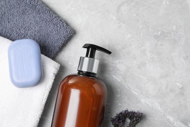 Photo of Soap bar, dispenser and terry towels on light grey table, flat lay. Space for text