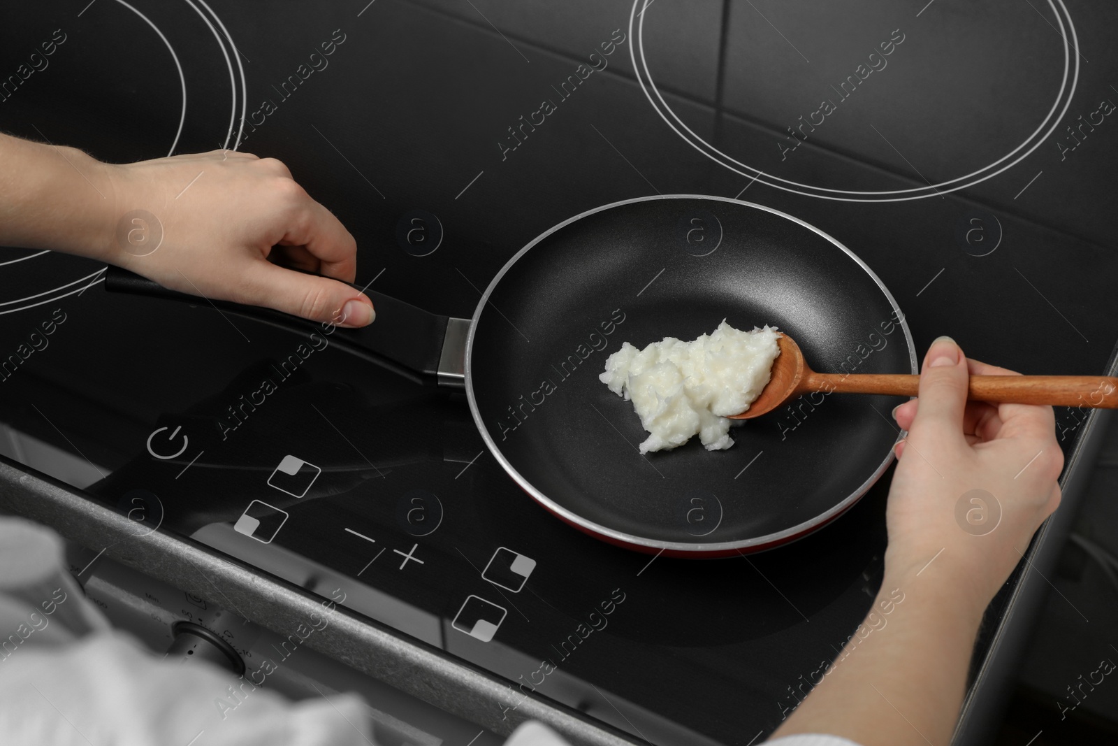 Photo of Woman cooking with coconut oil on induction stove, closeup