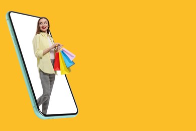 Image of Online shopping. Happy woman with paper bags walking out from smartphone on orange background, space for text
