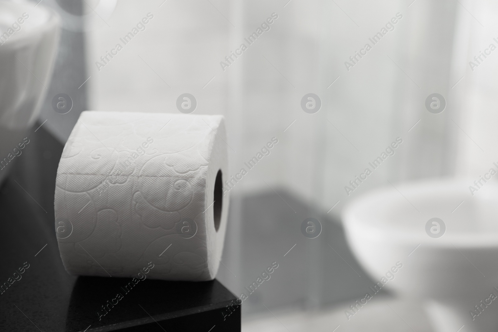 Photo of Toilet paper roll on table in bathroom. Space for text