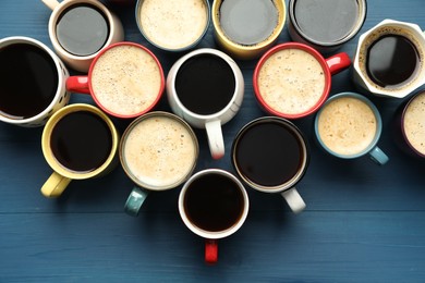 Many cups of different coffee drinks on blue wooden table, flat lay