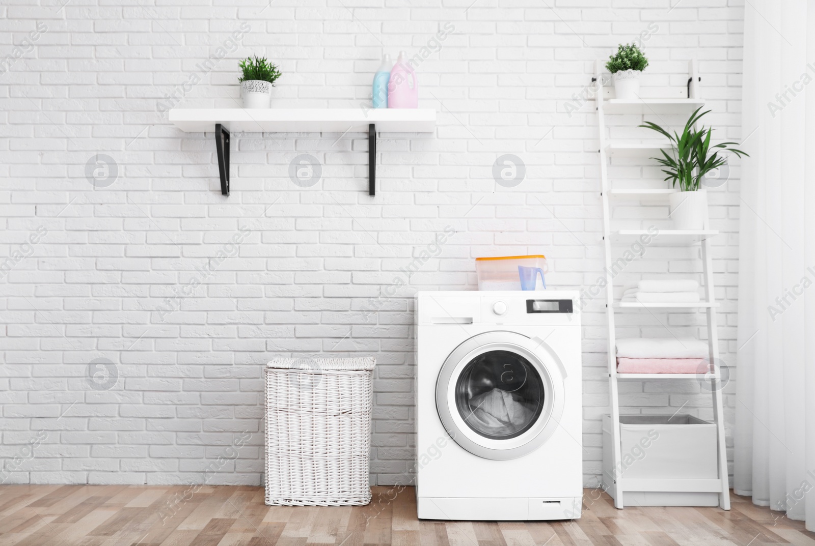 Photo of Modern washing machine near brick wall in laundry room interior, space for text