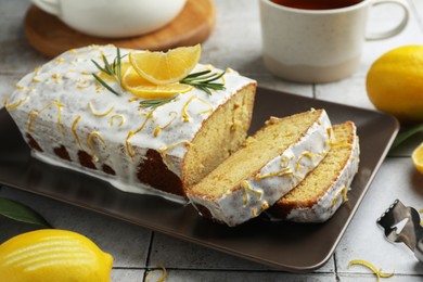 Tasty lemon cake with glaze and citrus fruits on table, closeup