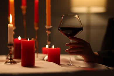 Beautiful young woman with glass of wine at table in restaurant, closeup