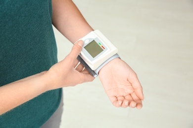 Photo of Young woman checking pulse with blood pressure monitor on wrist, closeup