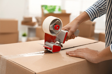 Photo of Woman packing cardboard box indoors, closeup. Moving day