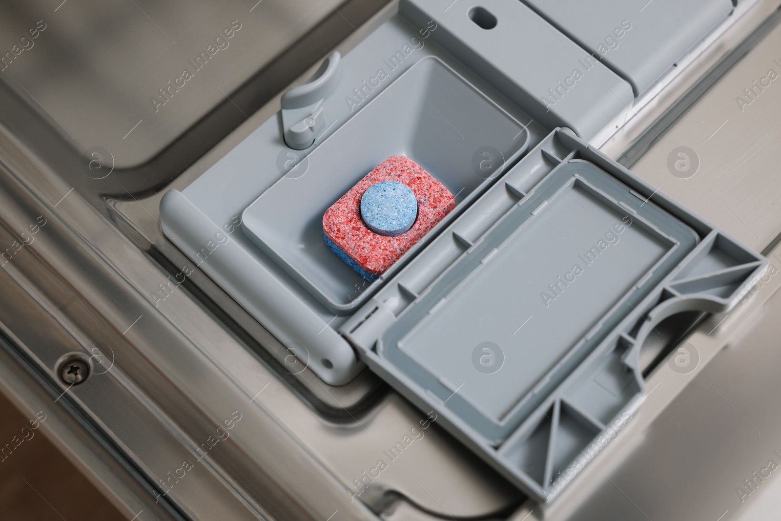 Photo of Open dishwasher door with detergent tablet, closeup