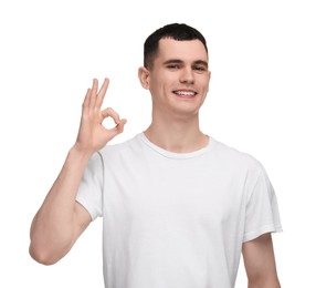 Photo of Handsome young man with clean teeth smiling and showing OK gesture on white background