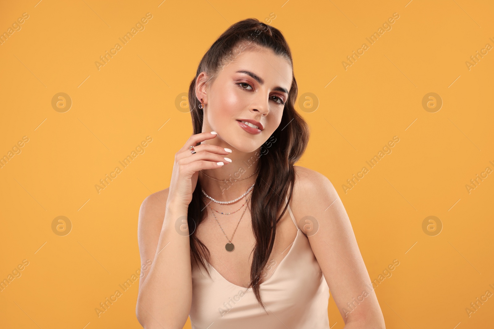 Photo of Beautiful woman with elegant jewelry on orange background