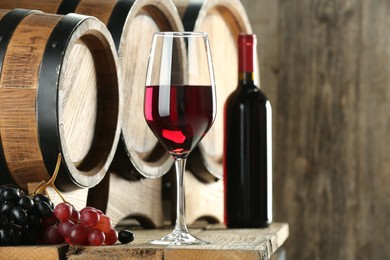 Photo of Winemaking. Composition with tasty wine and barrels on wooden table, space for text