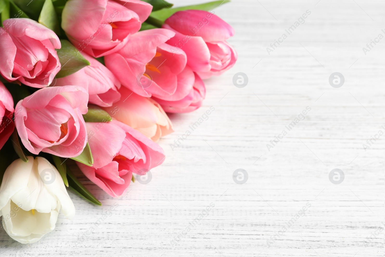 Photo of Beautiful spring tulips on wooden background, space for text. International Women's Day