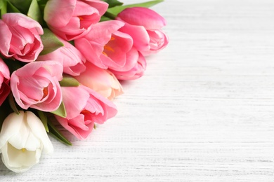 Photo of Beautiful spring tulips on wooden background, space for text. International Women's Day