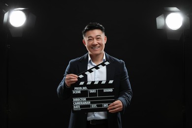 Happy asian actor with clapperboard on stage. Film industry