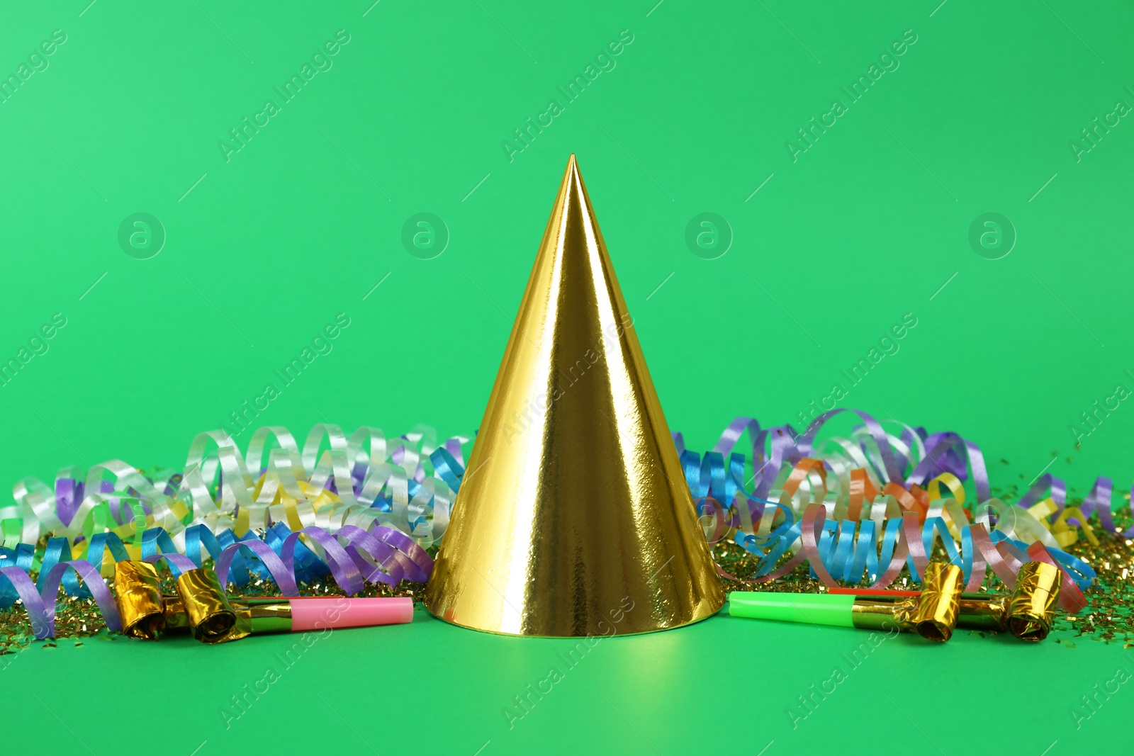 Photo of Colorful serpentine streamers, party cap and horns on green background