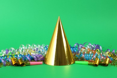 Photo of Colorful serpentine streamers, party cap and horns on green background