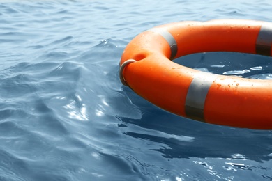 Photo of Orange life buoy floating in sea, closeup. Emergency rescue equipment