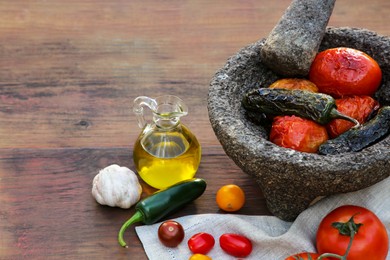 Ingredients for tasty salsa sauce, pestle and mortar on wooden table, space for text