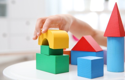 Photo of Cute child playing with colorful blocks at home, closeup