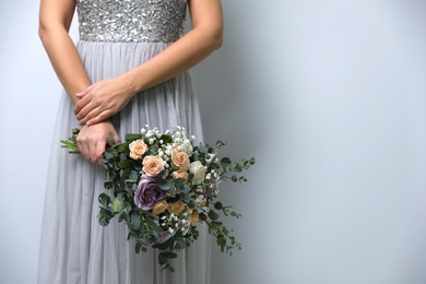 Photo of Bride holding beautiful wedding bouquet on light grey background, closeup. Space for text