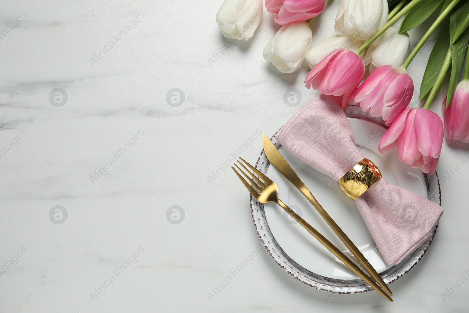 Photo of Stylish table setting with cutlery and tulips on white marble background, flat lay. Space for text