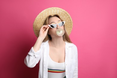 Photo of Fashionable young woman blowing bubblegum on pink background