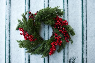 Beautiful Christmas wreath on metal surface covered with snow, top view
