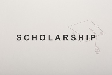 Word SCHOLARSHIP and academic cap on white paper