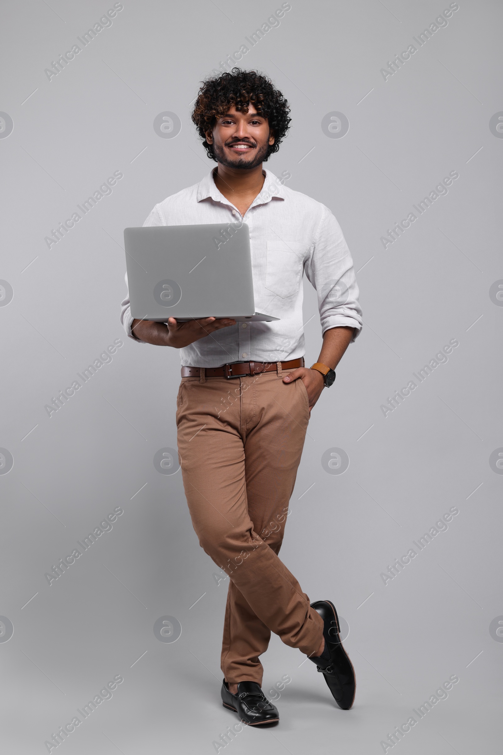 Photo of Smiling man with laptop on light grey background