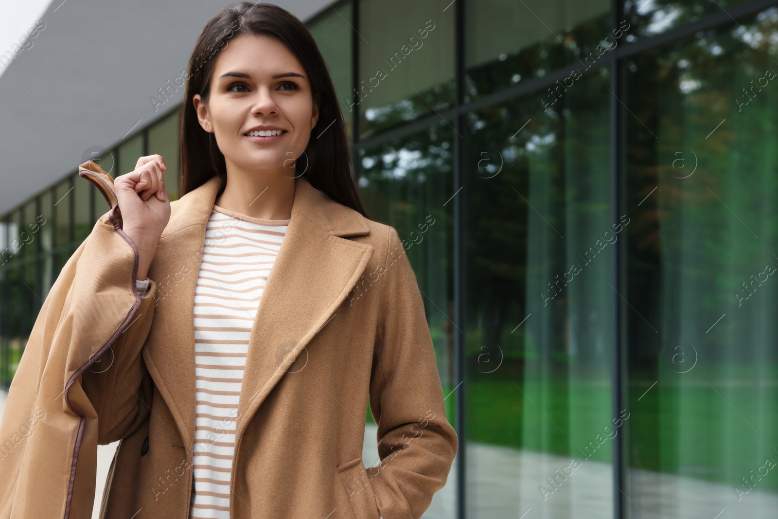 Photo of Attractive happy woman holding garment cover with clothes outdoors. Dry cleaning service