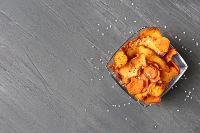 Photo of Bowl of sweet potato chips and salt on grey table, top view. Space for text