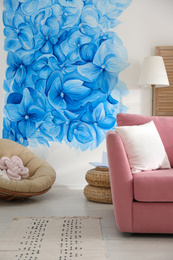 Photo of Stylish living room with blue flowers painted on wall. Floral pattern in interior design