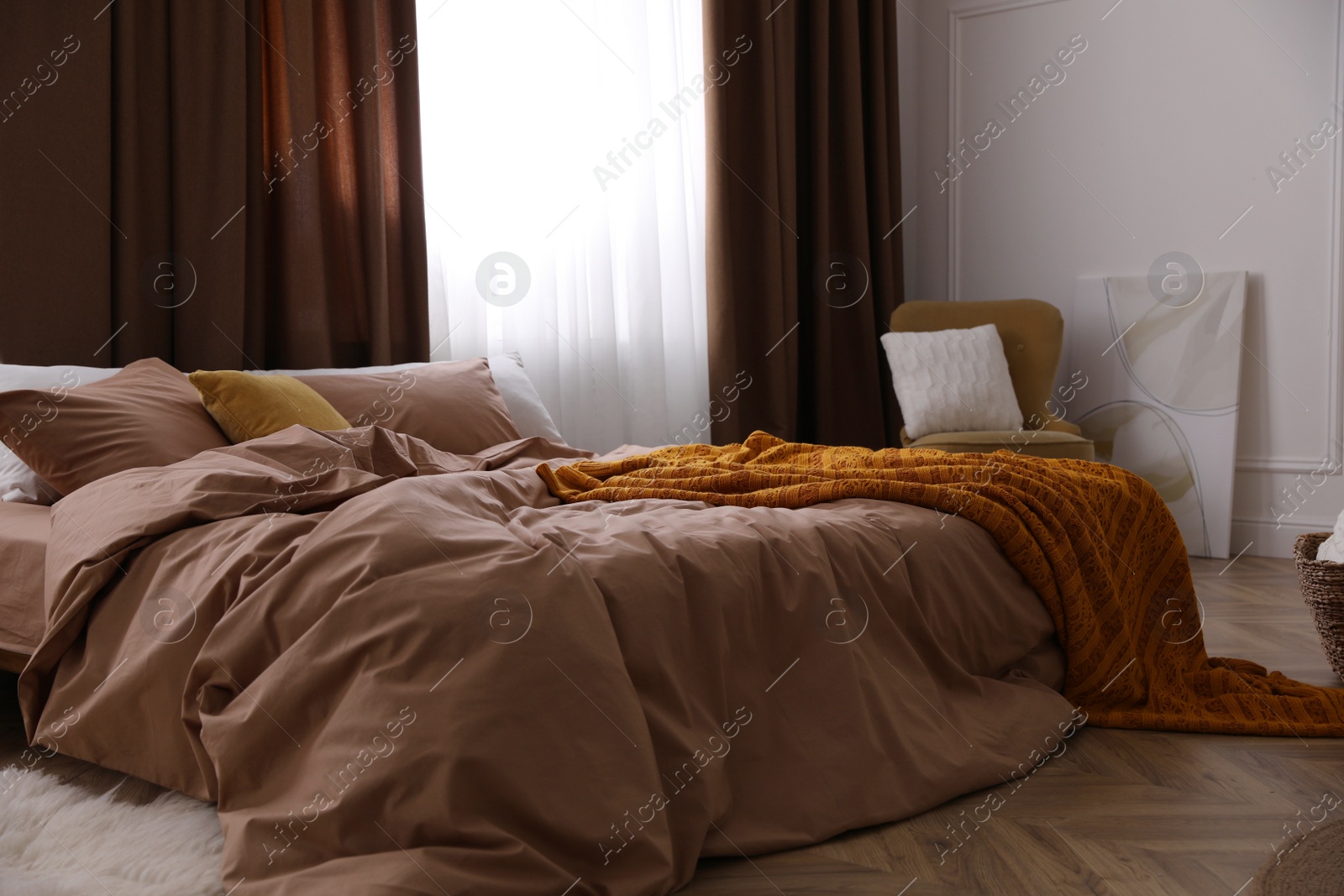 Photo of Bed with brown linens in stylish room interior
