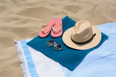 Blanket with blue towel and beach accessories on sand