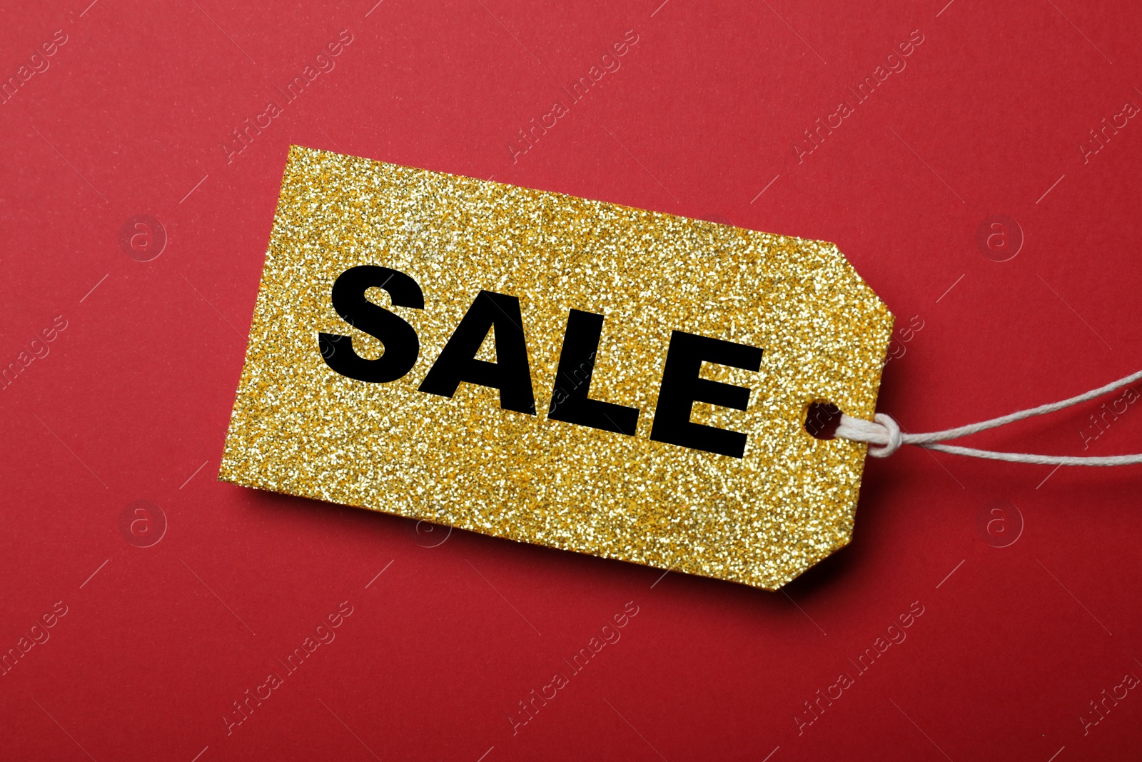 Photo of Golden tag with word Sale on red background, top view. Black Friday