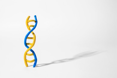 Photo of DNA molecule model made of colorful plasticine on white background, space for text