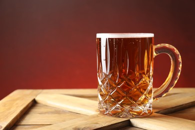Photo of Mug with fresh beer on wooden crate against color background. Space for text