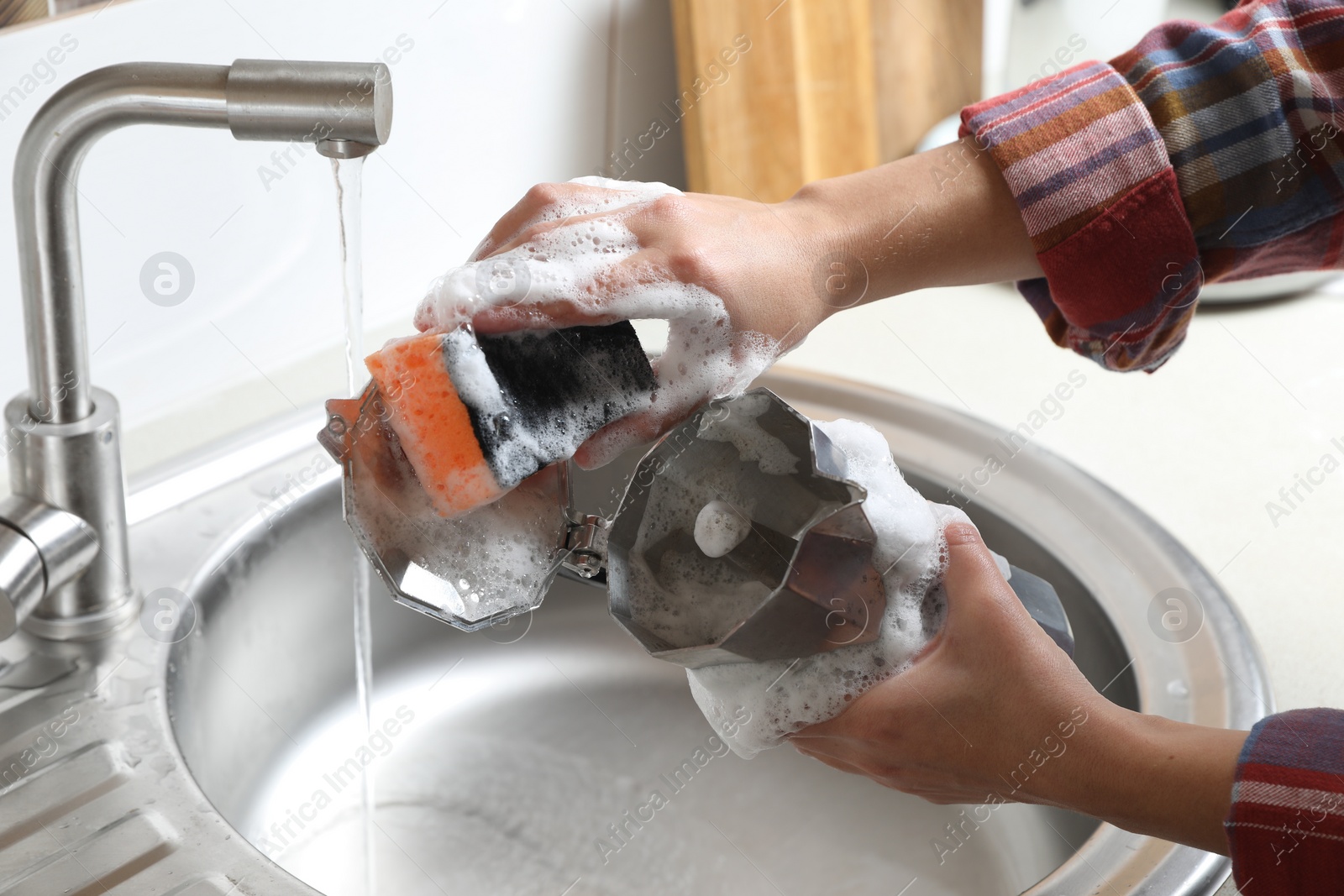 Photo of Woman washing moka pot (coffee maker) above sink in kitchen, closeup