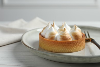 Tartlet with meringue on white wooden table, closeup and space for text. Delicious dessert