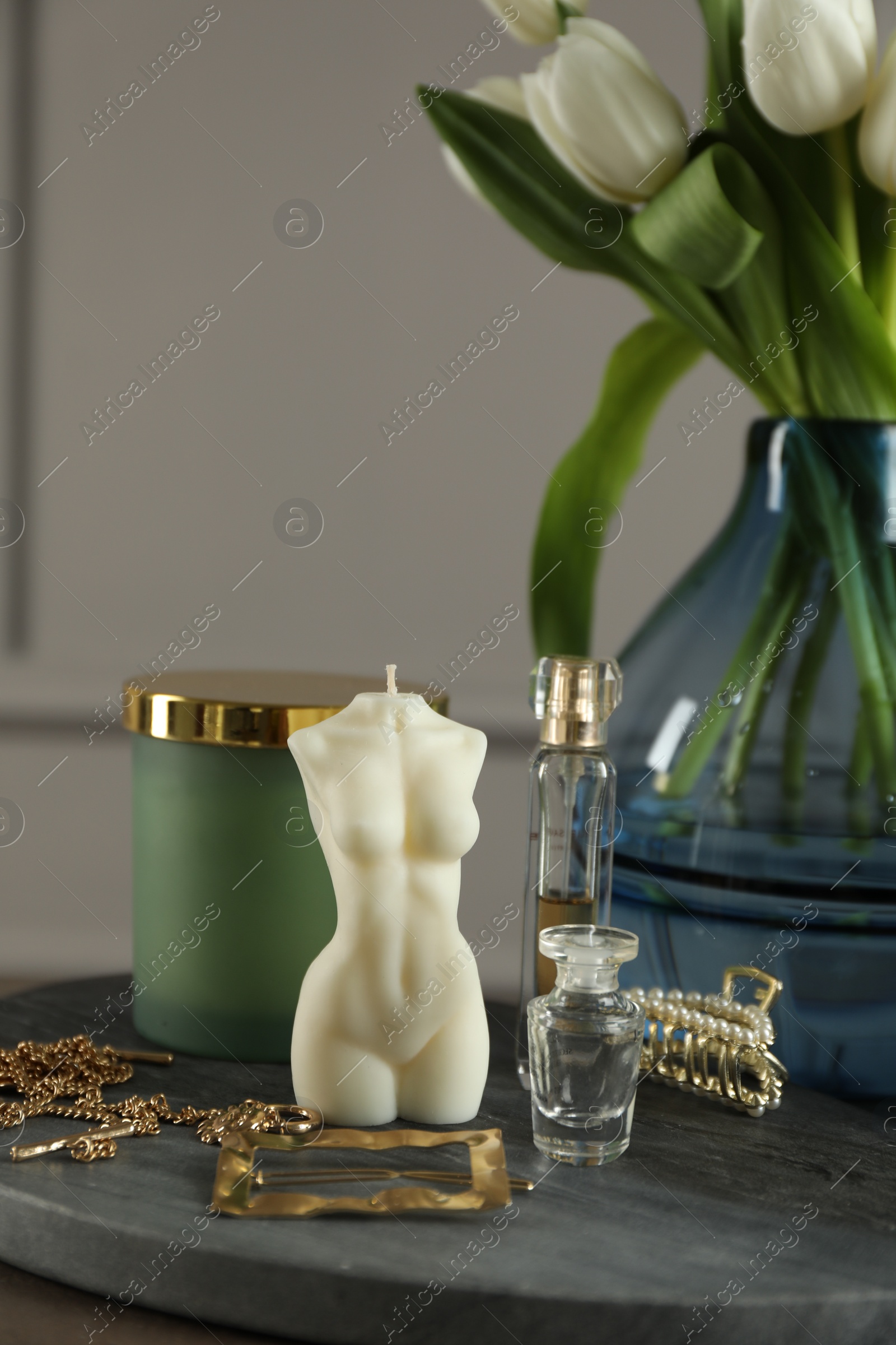 Photo of Beautiful female body shape candle, flowers and decor on table