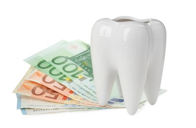 Photo of Ceramic model of tooth and euro banknotes on white background. Expensive treatment