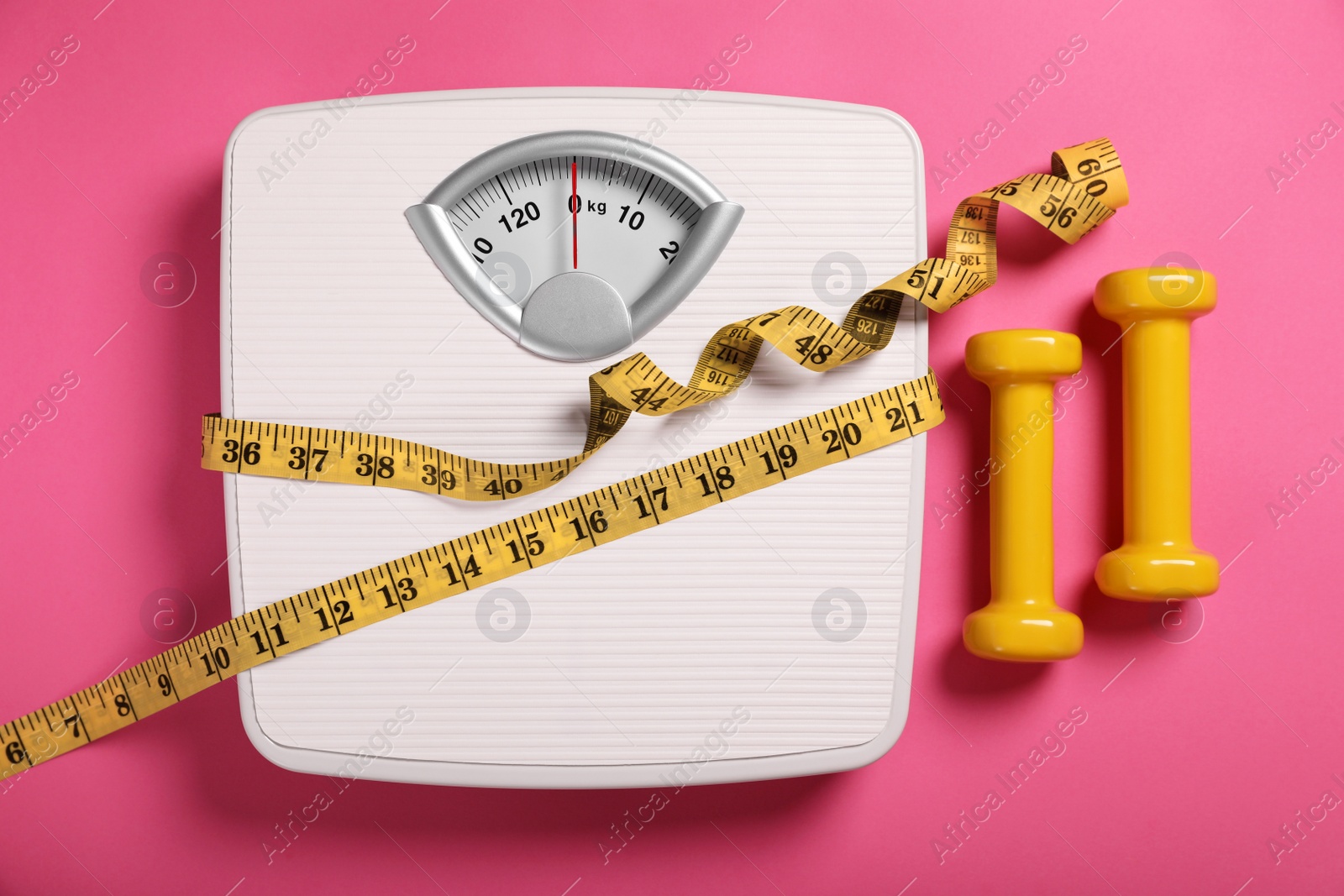 Photo of Weight loss concept. Scales, dumbbells and measuring tape on pink background, flat lay