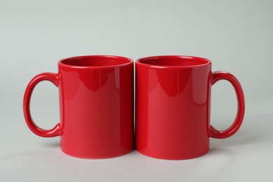 Photo of Two red ceramic mugs on light grey background