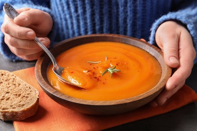 Photo of Woman eating tasty sweet potato soup at table, closeup