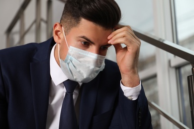 Sad man in protective mask indoors. Self-isolation during coronavirus pandemic