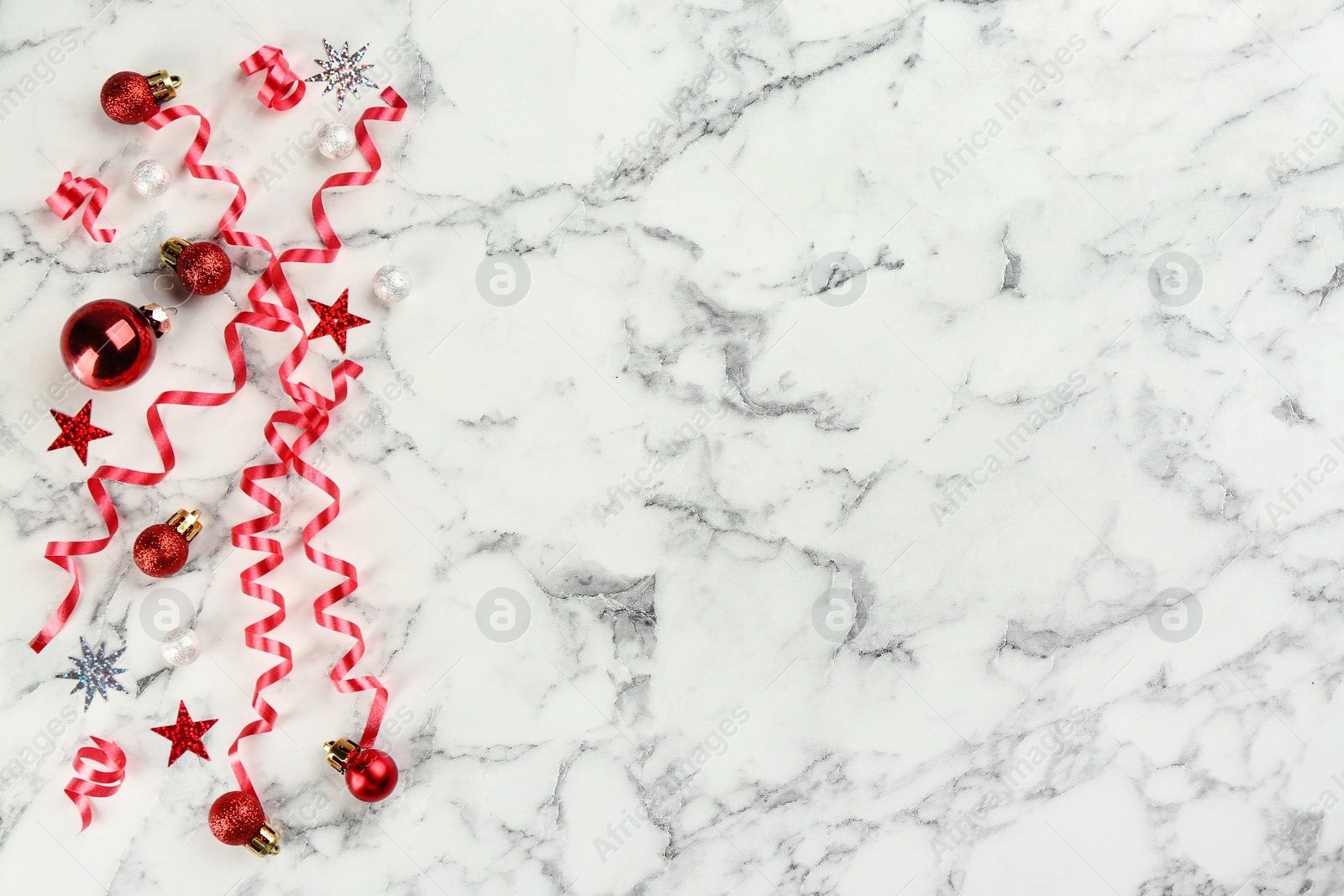 Photo of Red serpentine streamers and Christmas balls on white marble background, flat lay. Space for text